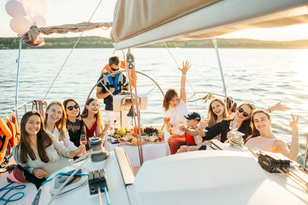 Friends toasting at a celebration table on a sailing yacht at golden hour